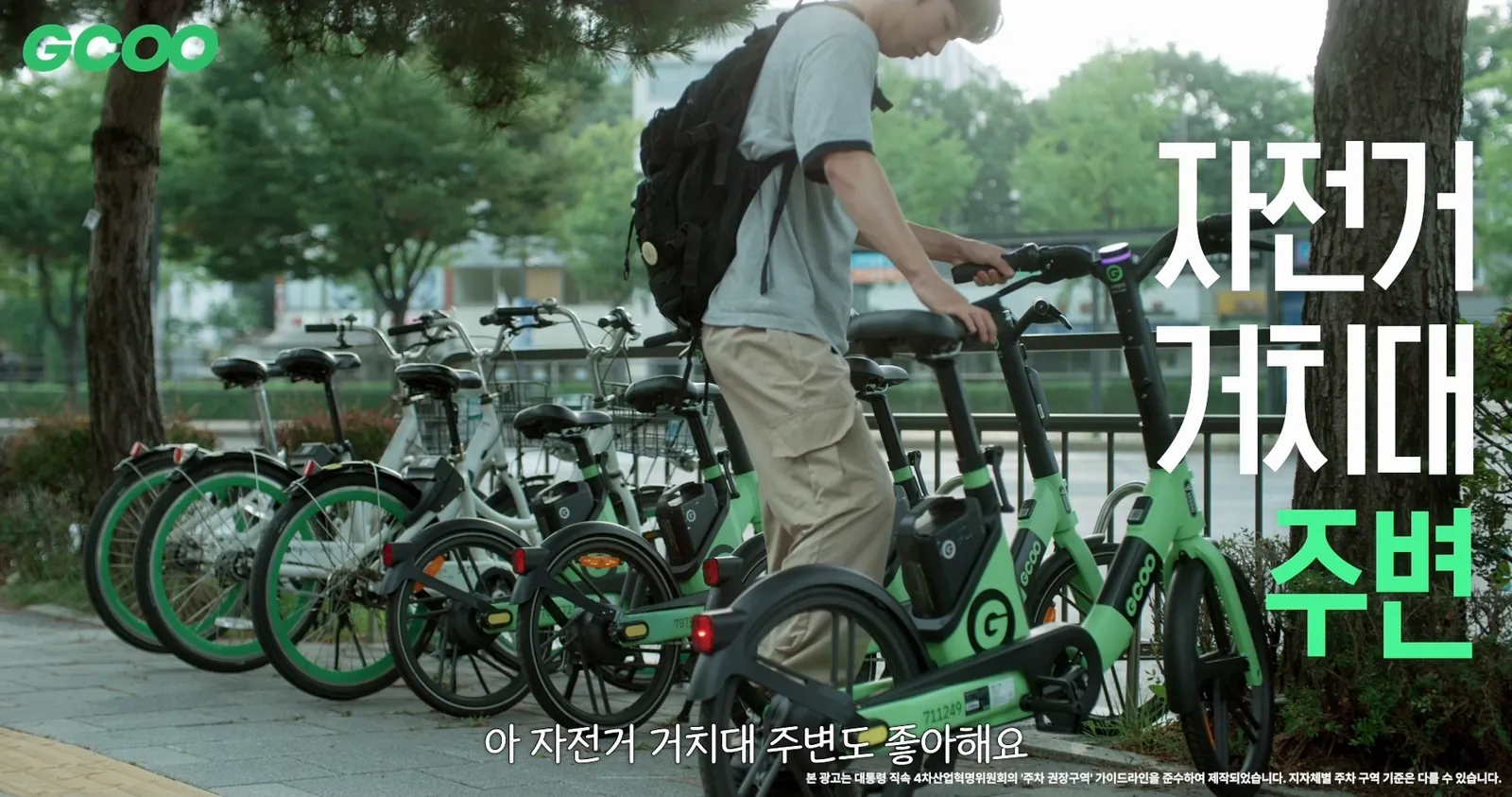A rider parking a GCOO bike next to a bike rack, with the on-screen text ‘Around bike racks’
