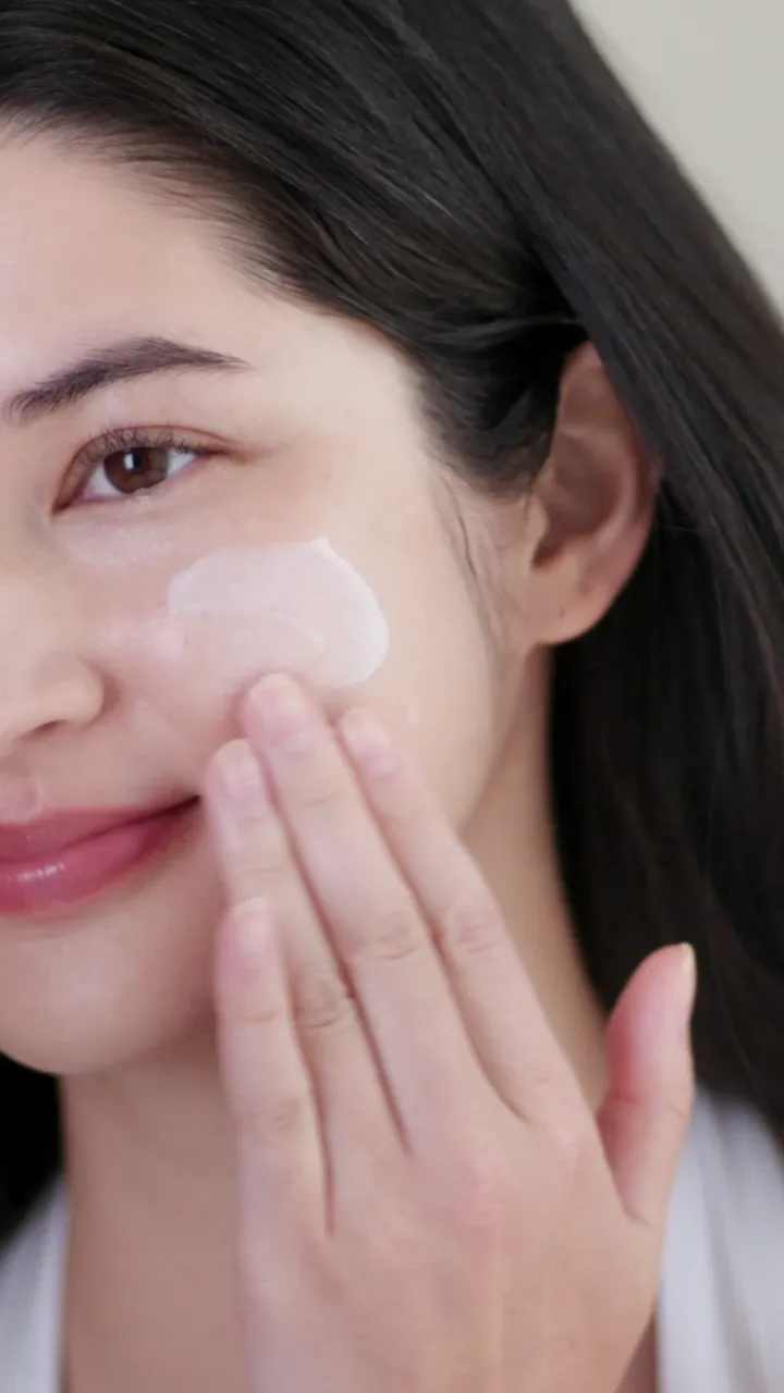 Model spreading sun serum on her cheek
