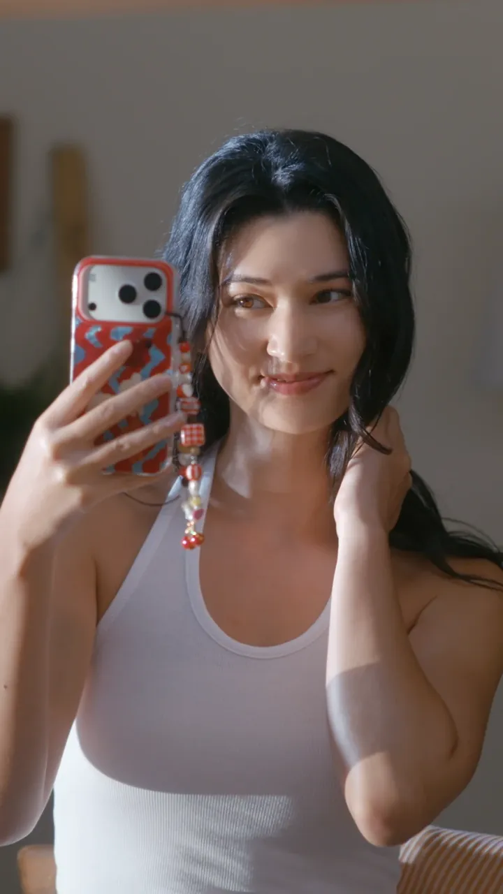 Model taking a mirror selfie in sunlight