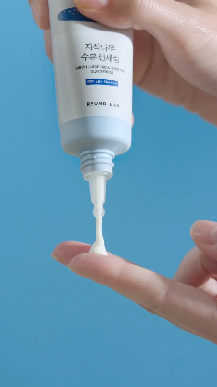 Sun serum squeezed onto a finger against a blue background